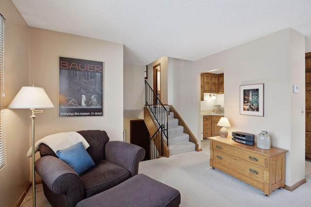 living area with light carpet, stairway, a textured ceiling, and baseboards