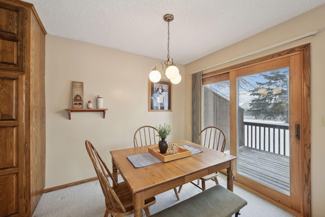 dining area featuring an inviting chandelier, baseboards, a textured ceiling, and light colored carpet