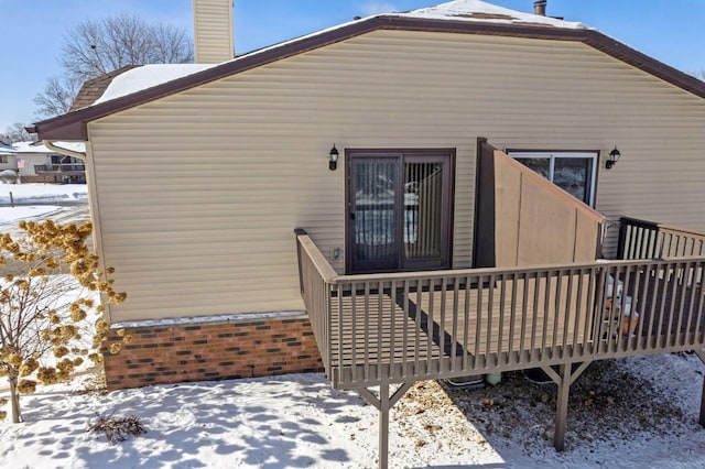 snow covered rear of property with a chimney