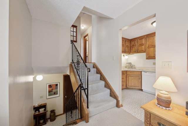 staircase with carpet floors, baseboards, and a textured ceiling