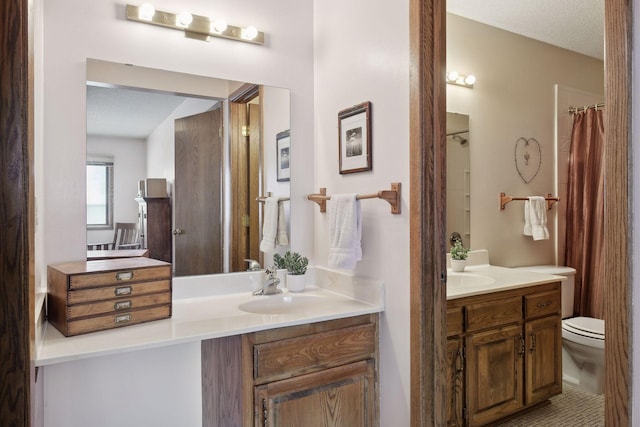 full bath featuring two vanities, a sink, and toilet