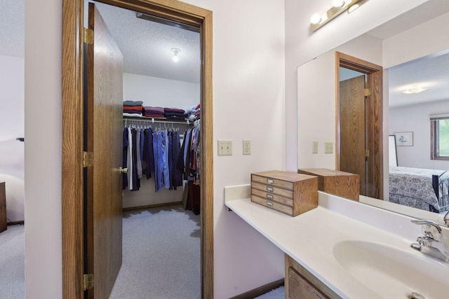 bathroom with a walk in closet, a textured ceiling, and vanity