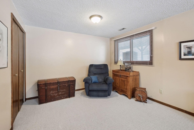 sitting room with a textured ceiling, carpet, visible vents, and baseboards