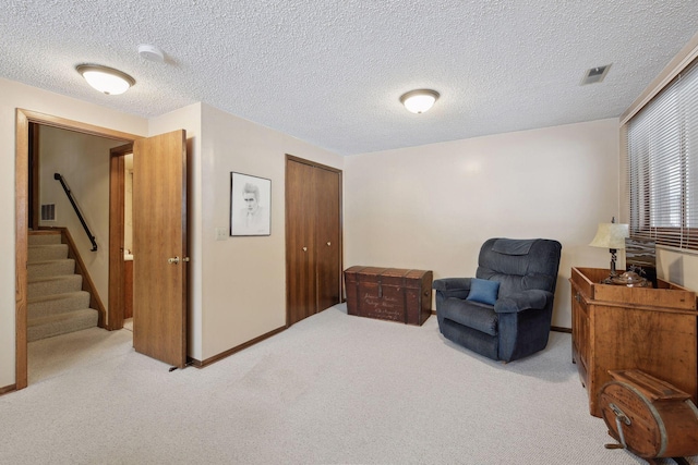 living area with a textured ceiling, visible vents, baseboards, stairway, and carpet