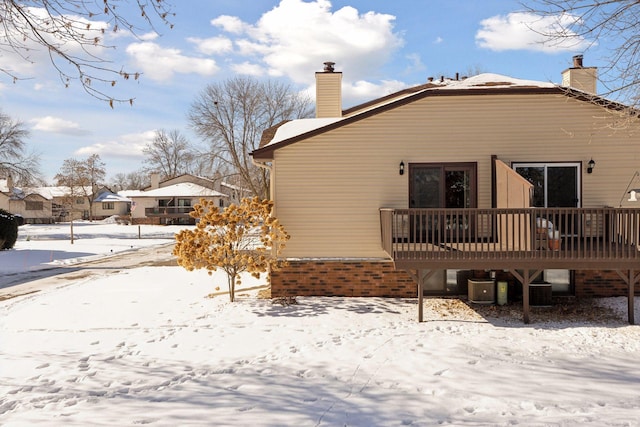 snow covered property with a chimney and a deck