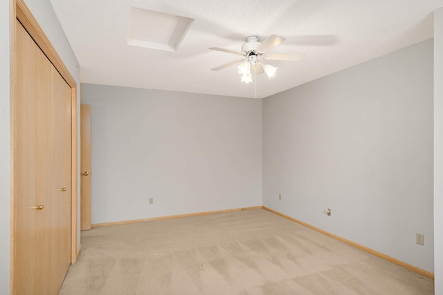 spare room with a ceiling fan, baseboards, a textured ceiling, and light colored carpet