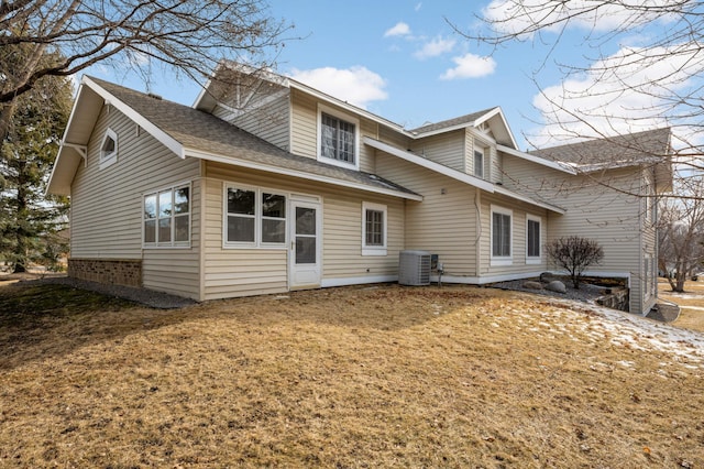 rear view of house featuring a yard, a shingled roof, and central air condition unit