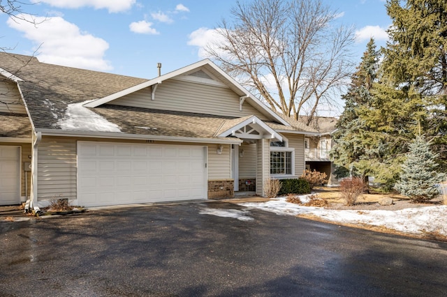 view of front of home with a garage, driveway, and a shingled roof