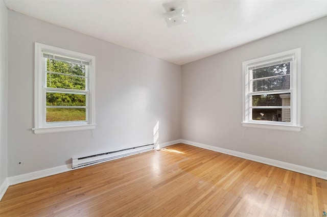 empty room featuring a baseboard heating unit and light hardwood / wood-style floors