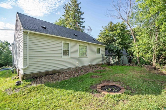 view of side of home featuring a yard and an outdoor fire pit