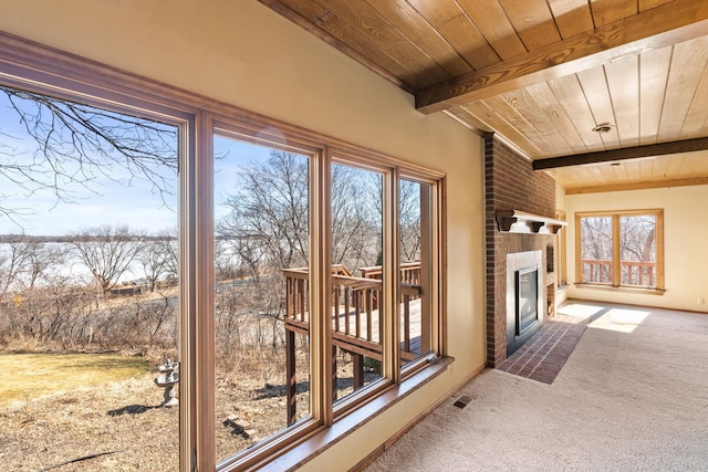 sunroom featuring a brick fireplace, wood ceiling, visible vents, and beamed ceiling