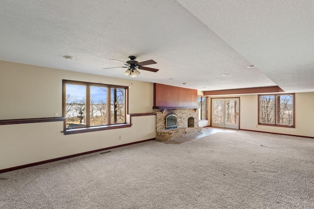 unfurnished living room featuring carpet, a brick fireplace, and plenty of natural light