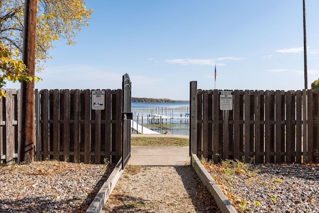 view of gate featuring a water view and fence