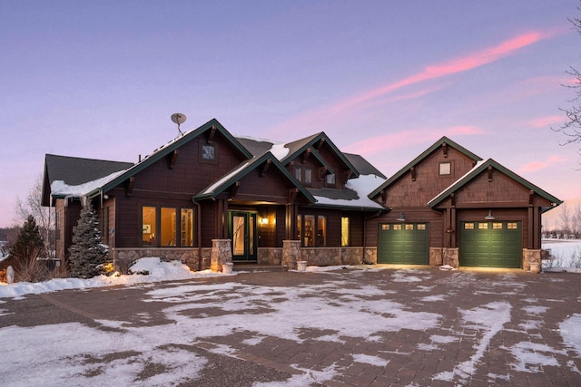 craftsman-style home with a garage, stone siding, and decorative driveway