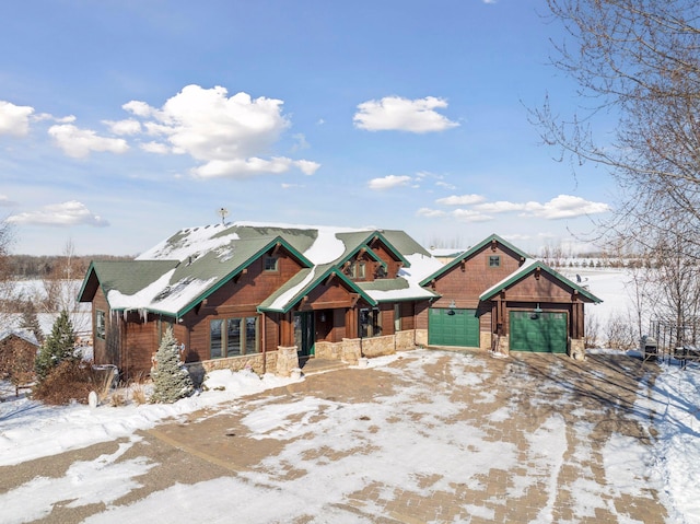 chalet / cabin featuring an attached garage and stone siding