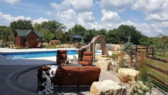 pool featuring a patio, a water slide, and an outdoor structure