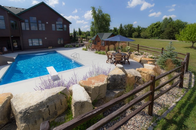 view of pool with a fenced in pool, a patio, fence, a water slide, and a diving board