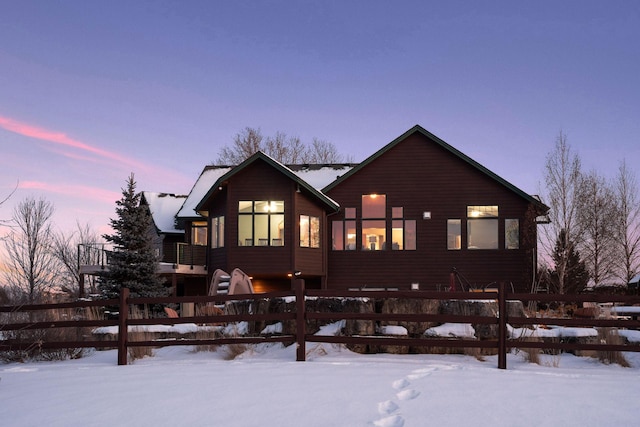 snow covered house with a fenced front yard