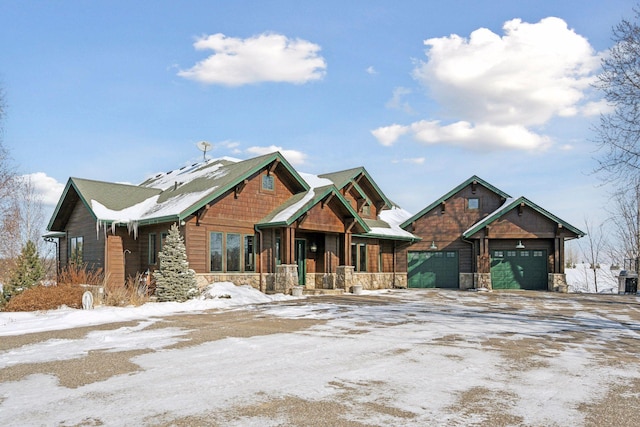 view of front of home featuring a garage, stone siding, driveway, and covered porch