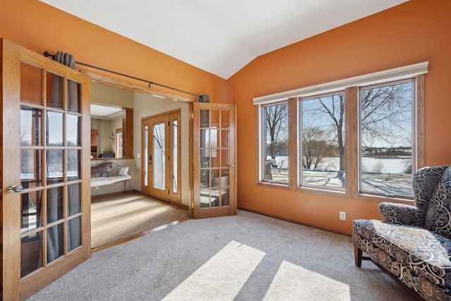 sitting room featuring french doors, light carpet, and vaulted ceiling