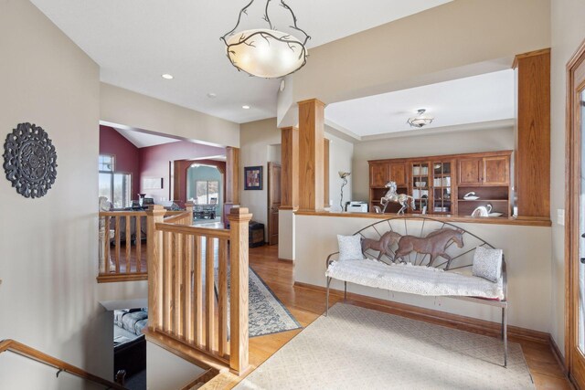 interior space featuring lofted ceiling, arched walkways, baseboards, light wood finished floors, and ornate columns