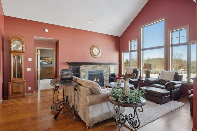 living room with high vaulted ceiling, a fireplace, and wood finished floors