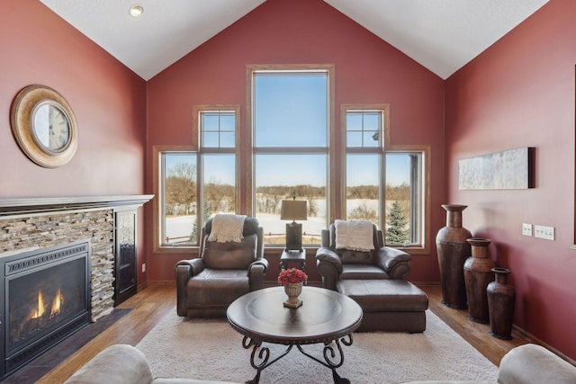 living room with plenty of natural light, wood finished floors, and a stone fireplace