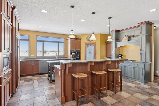 kitchen featuring a center island, decorative light fixtures, appliances with stainless steel finishes, a sink, and a kitchen bar