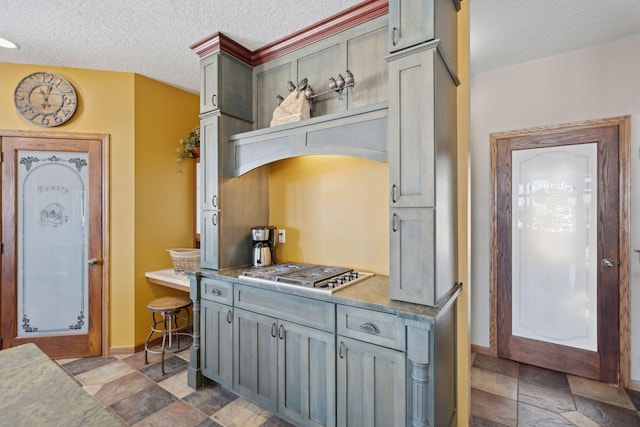 kitchen featuring baseboards, stainless steel gas cooktop, a textured ceiling, and gray cabinetry