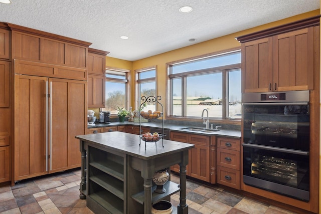 kitchen featuring dark countertops, double oven, open shelves, and a sink