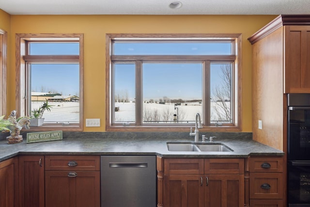 kitchen featuring dark countertops, stainless steel dishwasher, brown cabinets, and a sink