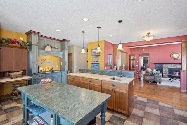 kitchen with a large island, a sink, decorative light fixtures, and brown cabinets