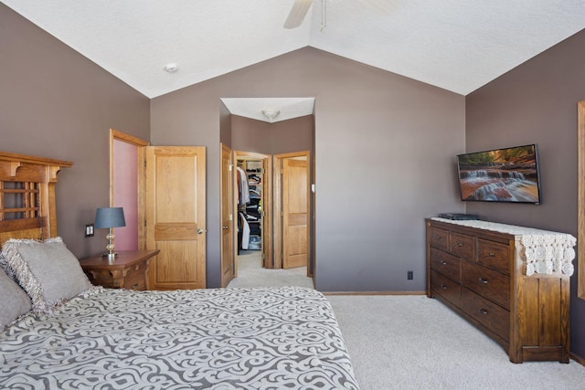 bedroom featuring lofted ceiling, light colored carpet, baseboards, a closet, and a walk in closet