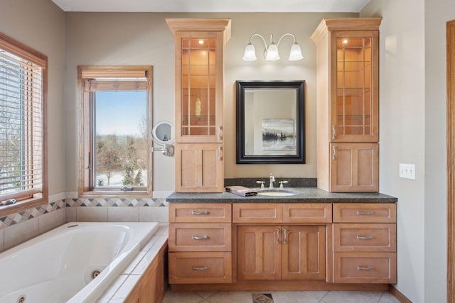 full bath featuring a jetted tub, vanity, and tile patterned floors