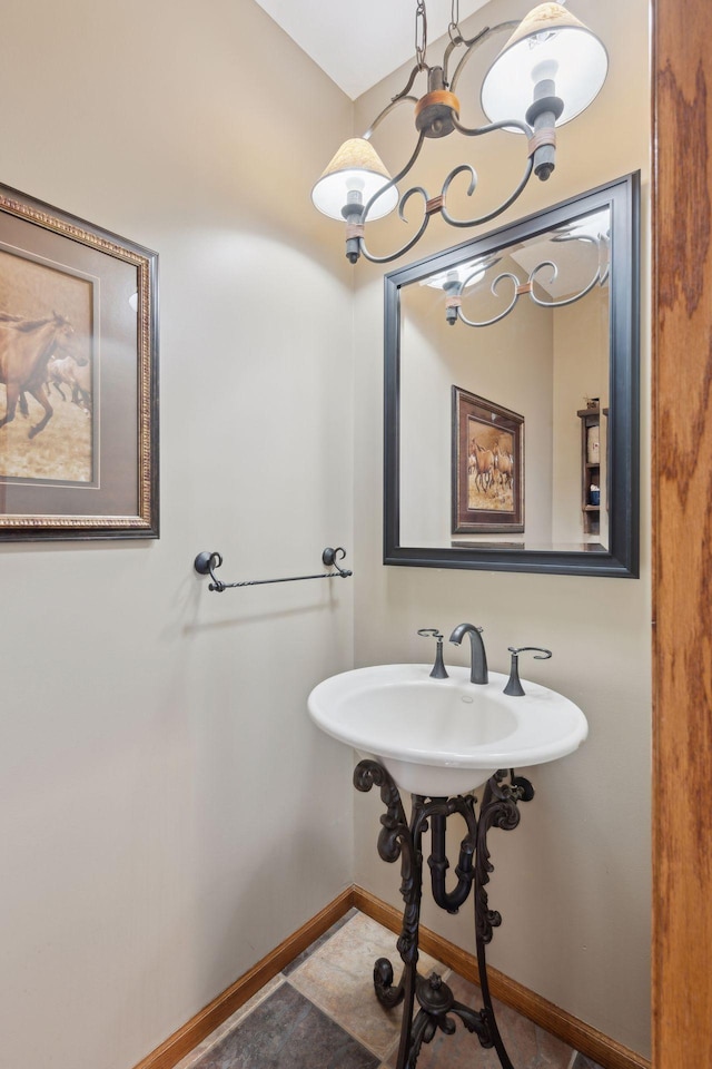 bathroom featuring baseboards and a chandelier