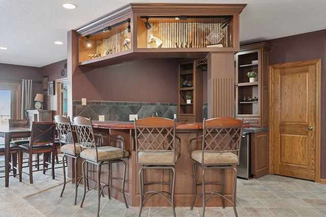 kitchen with a breakfast bar, a peninsula, a textured ceiling, open shelves, and recessed lighting