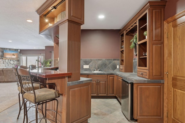 bar featuring backsplash, a textured ceiling, fridge, a sink, and recessed lighting