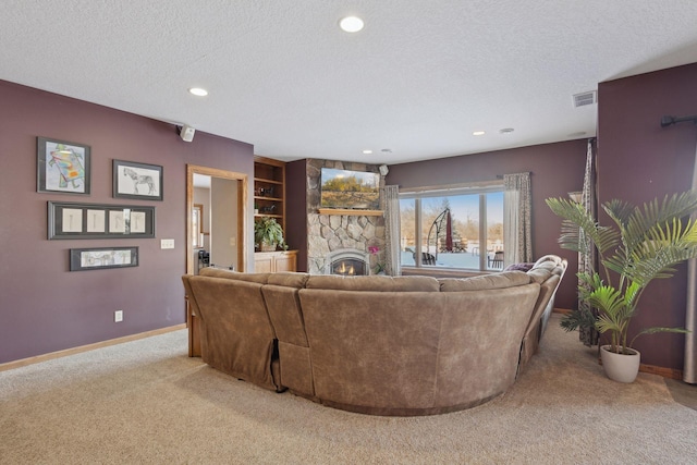 living area with recessed lighting, light carpet, a stone fireplace, a textured ceiling, and baseboards