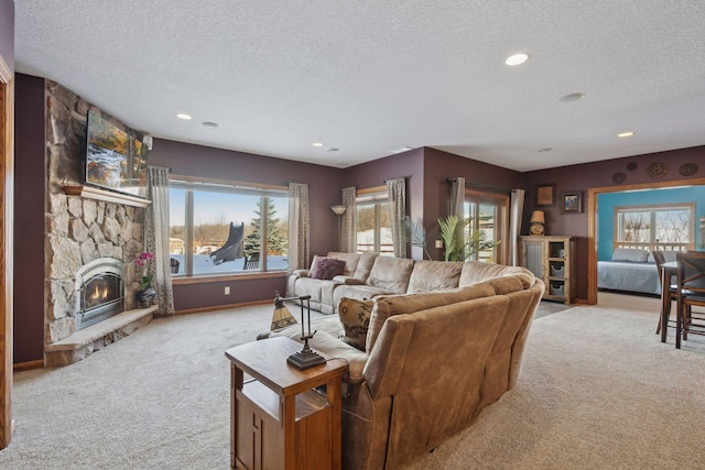 living room with light carpet, a stone fireplace, a textured ceiling, and recessed lighting