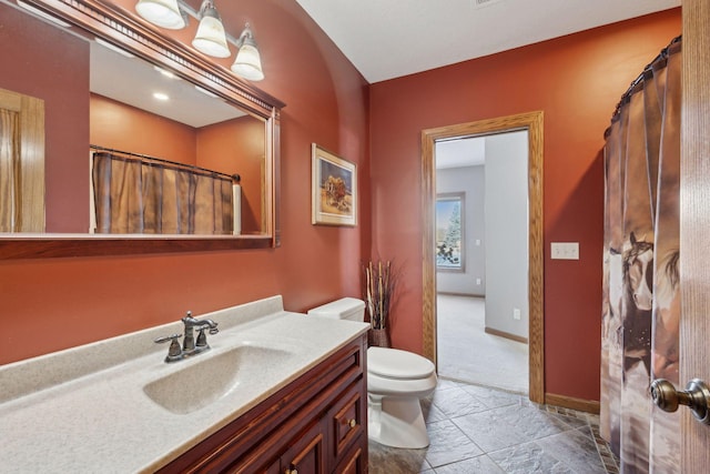 bathroom with baseboards, vanity, and toilet