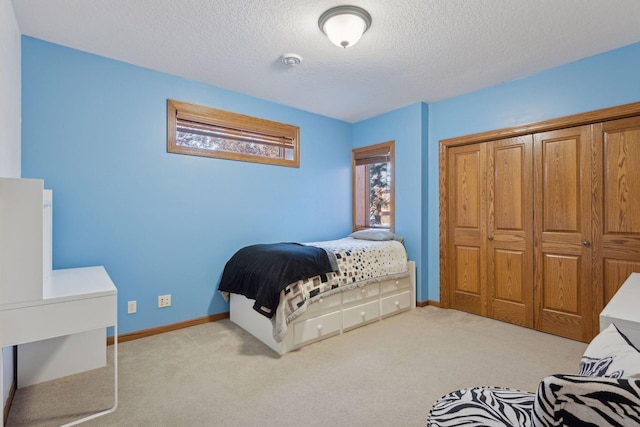 bedroom with light carpet, a textured ceiling, and baseboards