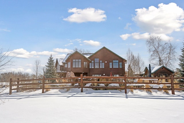 snow covered rear of property featuring a fenced front yard