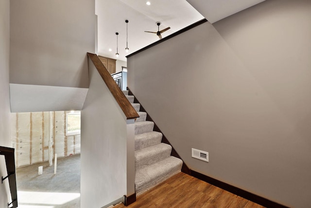 stairs with wood-type flooring and ceiling fan