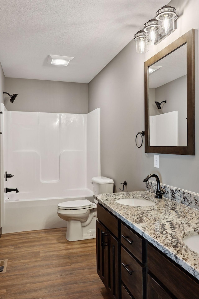 full bathroom with toilet, shower / bathing tub combination, a textured ceiling, vanity, and hardwood / wood-style floors