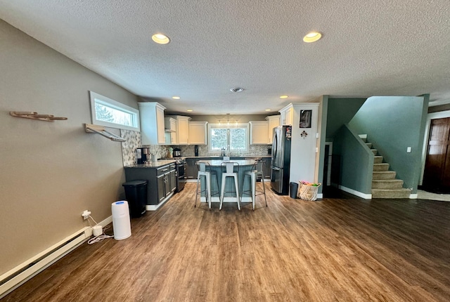 kitchen with a breakfast bar, white cabinetry, a baseboard heating unit, stainless steel appliances, and a kitchen island