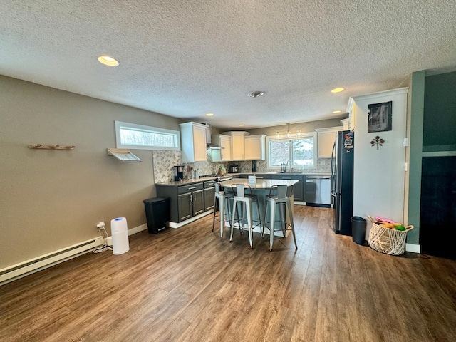 kitchen with wood-type flooring, a breakfast bar area, white cabinets, fridge, and a center island