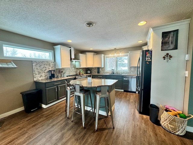 kitchen featuring sink, a breakfast bar, dishwasher, a kitchen island, and black fridge