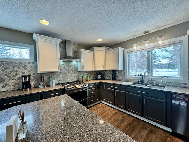 kitchen with sink, black dishwasher, wall chimney range hood, range with two ovens, and white cabinets