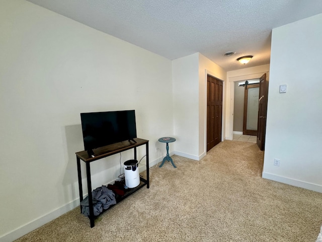 miscellaneous room with light colored carpet, a barn door, and a textured ceiling