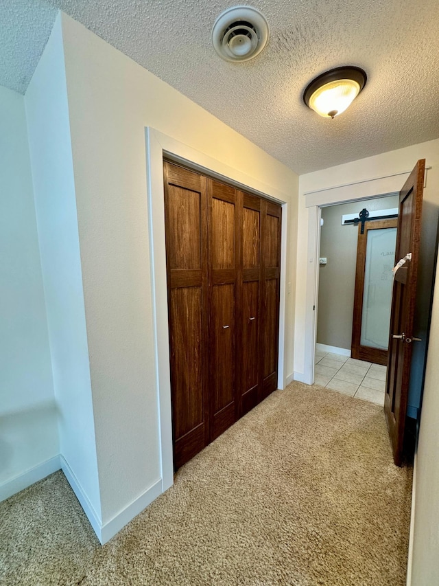 hall with light colored carpet and a textured ceiling